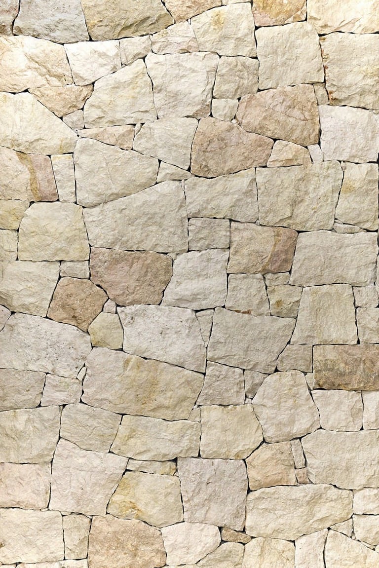Tan and beige irregular stone blocks tightly fitted together forming a textured wall or paving surface