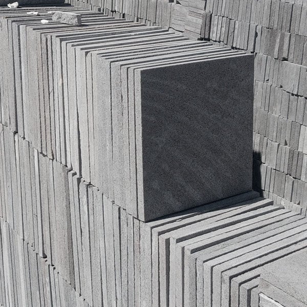 Stacked gray and black rectangular stone or concrete tiles arranged in rows outdoors, showing texture and depth