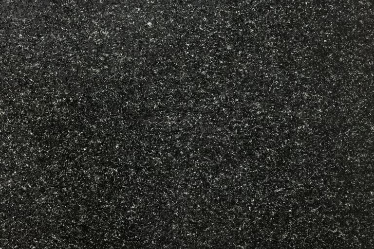 Close-up of dark speckled asphalt or granite surface with fine granular texture