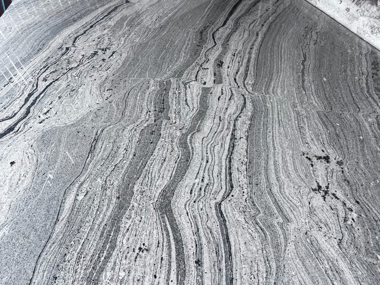 Aerial view of agricultural field with curved contour plowing lines and erosion patterns in gray soil