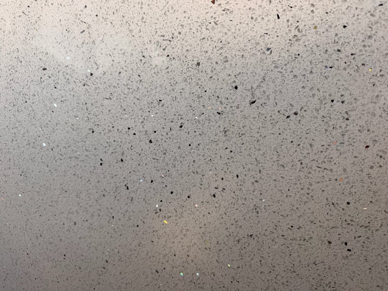 Close-up of concrete surface with scattered dark speckles and aggregate texture