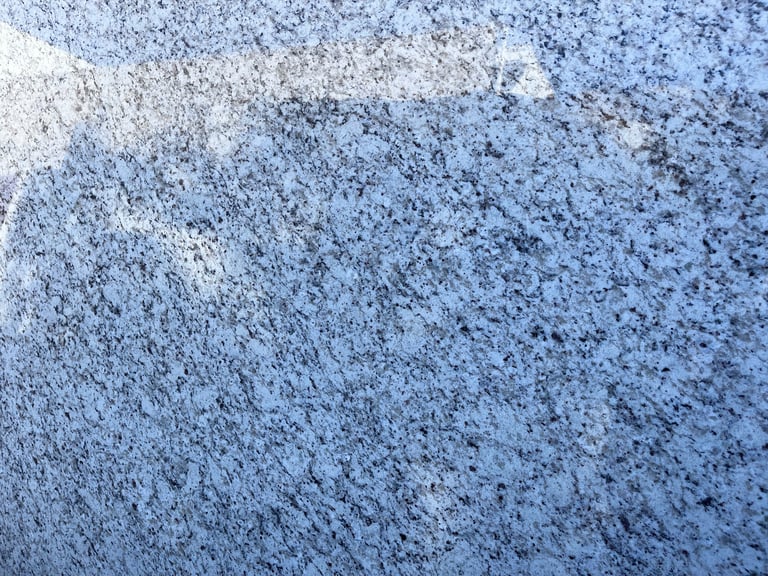 Close-up of a textured concrete or asphalt surface with frost and light snow coverage