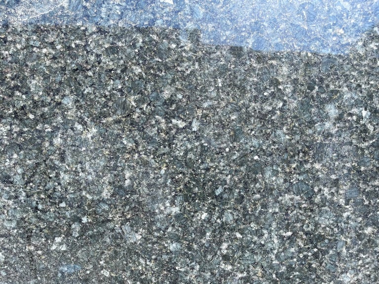 Close-up of rough concrete surface with white lichen or mold spots and blue sky reflection above