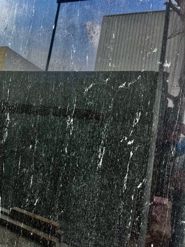 Heavy rain falling on a weathered green corrugated metal surface and nearby industrial structures