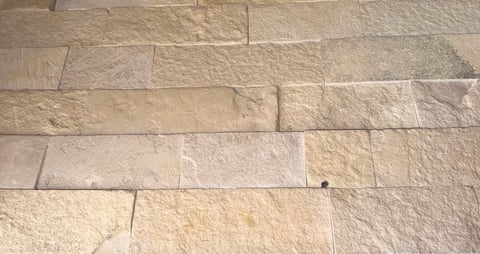 Close-up of light tan stone tiles or pavers with visible mortar grout lines between them
