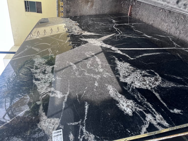 Overhead view of a large black water tank or pool with white mineral deposits and cracks, alongside a yellow building structure